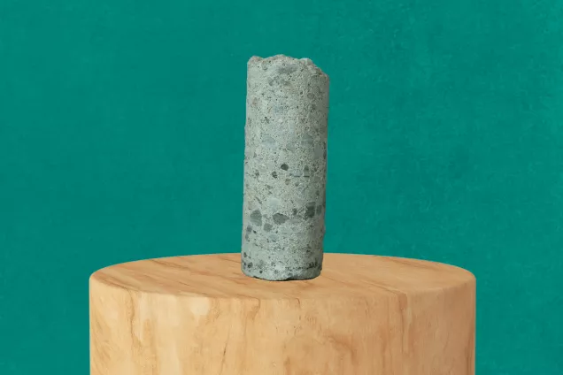 Cementcylinder på en träpiedestal mot en grön bakgrund. Illustration