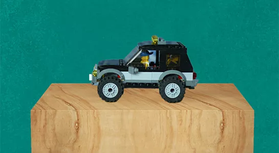 LEGO-bil av SUV-modell står på en piedestal av trä mot en grön bakgrund. Illustration. 